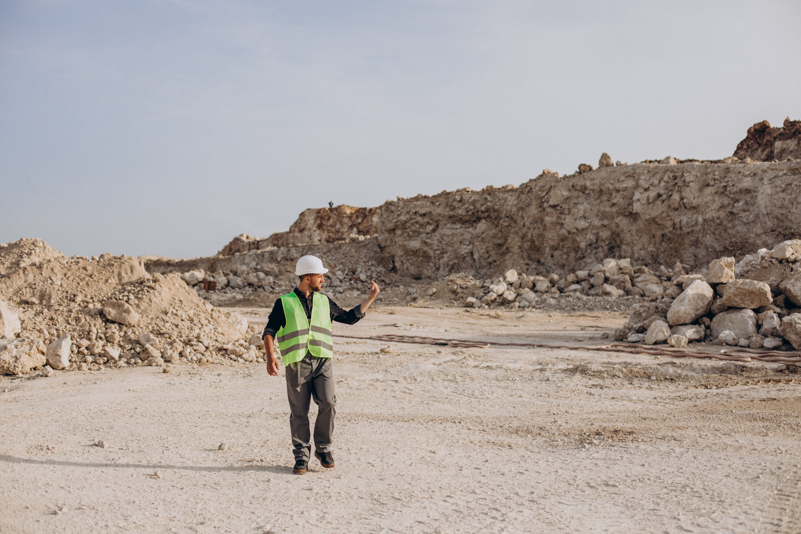 Worker in hardhat standing in sand quarry Worker in hardhat standing in sand quarry
